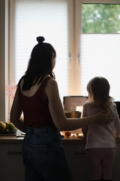 A still from a family drama film, showing a mother and daughter in a tense conversation in a kitchen setting, with natural light streaming through the window.