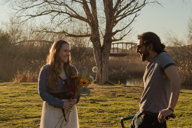 A candid still from a romantic movie scene shows a couple laughing joyfully together, portraying the blossoming of love in a scenic outdoor setting.