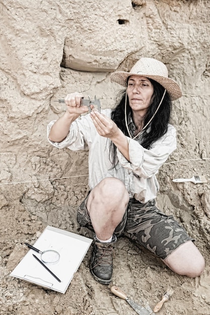 A young female archaeologist stands triumphantly atop a newly unearthed ziggurat in the scorching desert. She's holding up an ancient artifact that glints in the sunlight, and her determined expression reflects years of dedication leading to this pivotal discovery.
