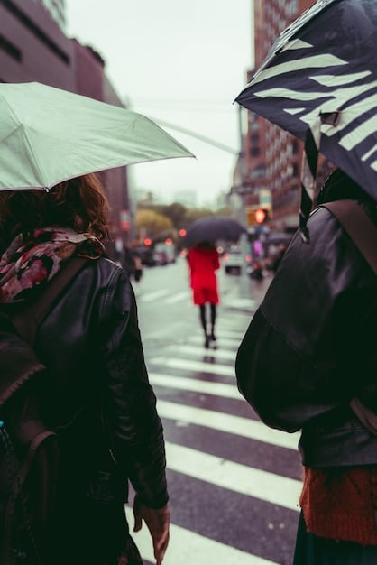 A group of people walking out of a studio, looking dejected. Rain is falling and the scene is shot in a desaturated color palette.