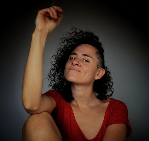 A close-up shot of a young Brazilian actress giving an emotional and powerful performance in a drama scene. The scene is dimly lit with a single spotlight on her face, highlighting her intense concentration and expressive facial features.