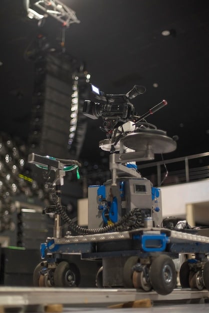 A behind-the-scenes shot of a Record TV reality show set, showing multiple cameras, lighting equipment, and crew members working diligently to capture the action. The set is vibrant and dynamic, reflecting the energy of the show.